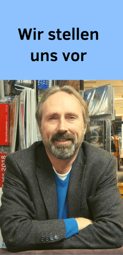 Foto eines Buchhändlers, der am Tisch vor Kalendern sitzt, Buchhandlung stellt sich vor